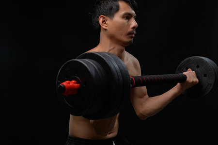A focused man lifts a heavy dumbbell showcasing strength and dedication in his fitness journey. Perfect for representing health, training, and body conditioning.の写真素材