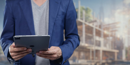 A business professional interacts with a tablet on a construction site, showcasing the integration of technology in modern construction management and project planning.の写真素材