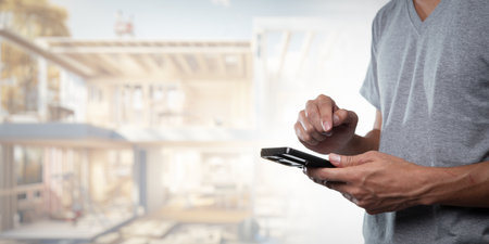 A professional engaged in construction technology using a smartphone for project management and design. Emphasizes innovation and connectivity in modern building practices.の写真素材