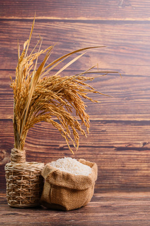 A charming still life featuring dried rice stalks and white rice in natural fiber bags, set against a rustic wooden background. Perfect for food and home decor themes.の写真素材