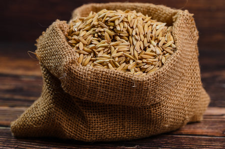 A fresh sack of natural brown rice sits on a rustic wooden table, showcasing the grain's unique texture and earthy tones. Perfect for culinary projects.の写真素材