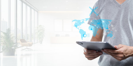 A business professional utilizes a tablet to plan travel abroad in a modern office setting. This image represents the blend of technology and global travel for professionals.の写真素材