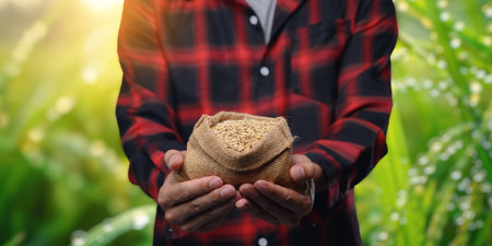 A rice grower proudly holds a sack of rice in a vibrant green field, symbolizing growth, agriculture, and the journey from farm to market in the world of trading.の写真素材
