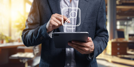 A professional person engaged in searching for information on a tablet in a modern office environment, highlighting the intersection of technology and business.の写真素材