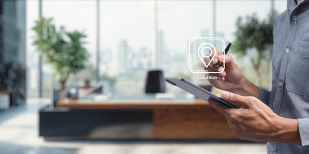 A person uses a tablet in a modern office space, showcasing an icon for pinning a destination location. The image represents a blend of technology and workspace design, ideal for illustrating business communication and planning.の写真素材