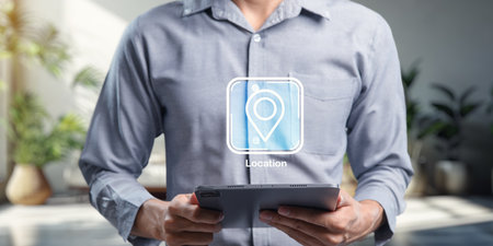A user holds a tablet displaying an icon for pinning a location to a destination. The modern office environment highlights technology and connectivity.の写真素材