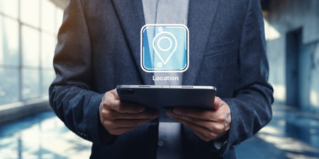 A businessman holds a tablet device featuring a digital icon representing location pinning. This imagery captures the fusion of technology and navigation in a modern workspace.の写真素材
