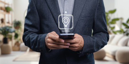 A professional holding a smartphone, featuring an icon for pinning a location in a modern workspace. This image captures the essence of digital navigation and connectivity.の写真素材