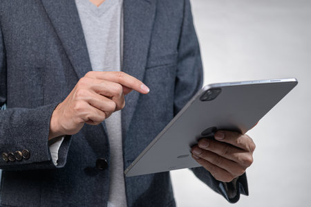 A business professional engages with a tablet in a modern office setting, showcasing technology interaction and contemporary work culture.の写真素材