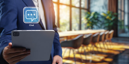 A business professional uses a tablet to interact with a customer via chat in a modern office setting, emphasizing collaboration and effective communication.の写真素材