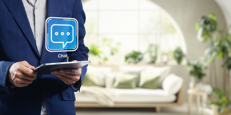 A professional in a suit holds a tablet, symbolizing modern business interaction. The digital chat icon suggests effective communication with customers and partners.の写真素材