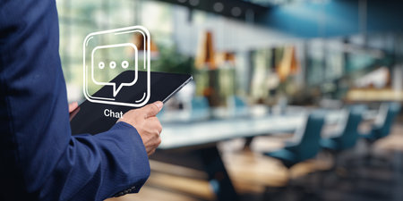 A professional individual interacts with a chat icon on a tablet in a modern office setting, symbolizing business collaboration and customer communication.の写真素材