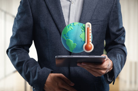 A businessman holds a tablet showcasing global temperature metrics, emphasizing the importance of technology in climate awareness and data analysis.の写真素材