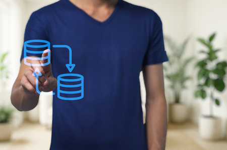 A man engages with digital data management concepts in a modern office. His interactive hand gesture illustrates data transfer and workflow efficiency.の写真素材