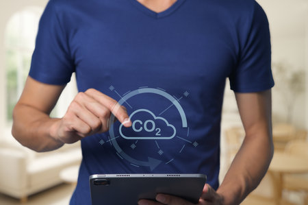 A person interacts with a tablet showcasing a carbon dioxide cloud icon, emphasizing the importance of tracking emissions and promoting environmental awareness.の写真素材