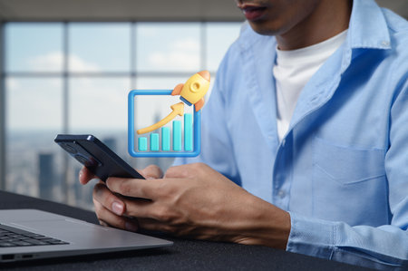 A business professional engages with a smartphone while an illustrative graph with an upward arrow symbolizes growth and success at a modern office setting.の写真素材