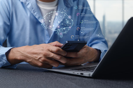A person uses a smartphone while analyzing data with AI tools on a laptop. This image illustrates modern technology, digital innovation, and the integration of advanced analytics for enhanced productivity.の写真素材