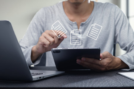 A person interacts with a tablet to manage digital documents in a modern workspace. The integration of technology enhances productivity and communication.の写真素材