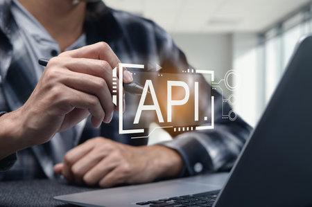 A programmer engages with an API interface on a laptop, showcasing modern software development practices in a collaborative and innovative workspace setting.の写真素材