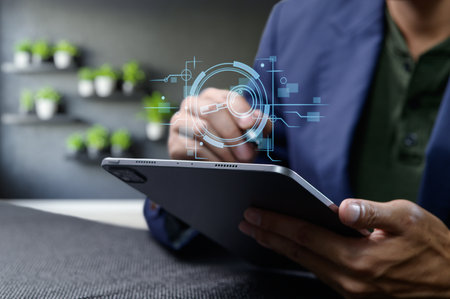 A professional individual interacts with a glass tablet, showcasing a digital icon for information searching. The modern design highlights user interaction with technology in a sleek workspace.の写真素材