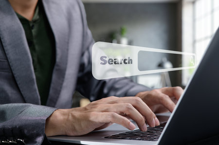 A businessman focused on his laptop, searching online for information. The scene showcases modern technology and a professional workspace, emphasizing productivity and innovation.の写真素材