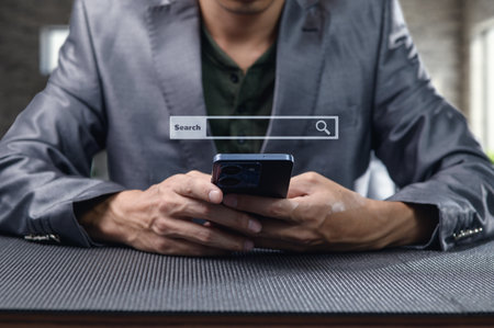 A professional man in a suit engages in online searching with his mobile device. The image captures the essence of modern technology and business interaction.の写真素材