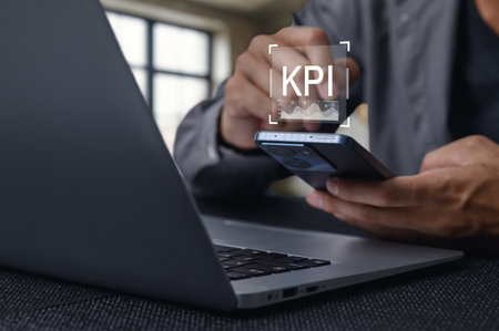 A business professional analyzes Key Performance Indicators using a laptop and smartphone, showcasing the importance of technology in data evaluation and strategic planning.の写真素材