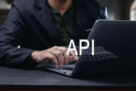 A close-up of a man working on a laptop, exploring concepts of programming interfaces, specifically API. The creative workspace showcases a blend of technology and innovation.の写真素材