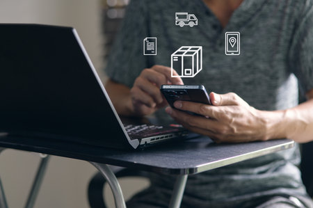 This image showcases a person using a smartphone and laptop to manage the delivery of goods globally, highlighting modern technology in logistics and e-commerce.の写真素材