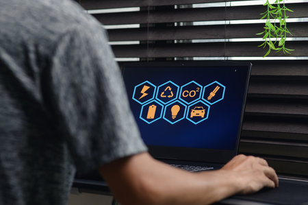 A person interacts with a computer screen displaying icons related to CO2, energy, and sustainability. This image emphasizes technology's role in addressing environmental issues.の写真素材