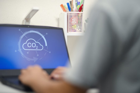 A person typing on a laptop showcases a conceptual image related to carbon dioxide emissions and...