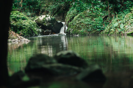 A tranquil scene capturing a beautiful waterfall flowing into still waters, surrounded by lush...