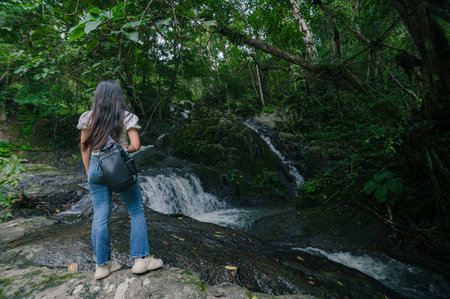 A woman enjoys the serene beauty of the North and South Jetkot Waterfalls, surrounded by lush...