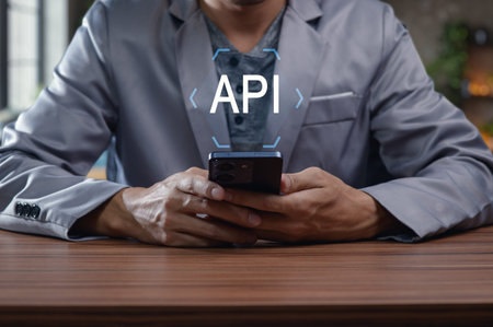 A professional developer interacts with a smartphone showcasing an API concept. The image highlights...