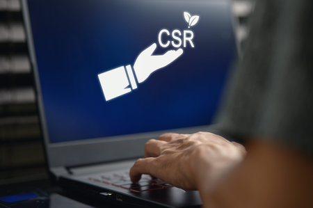 A hand reaching towards a laptop screen displaying the CSR acronym symbolizes corporate social...