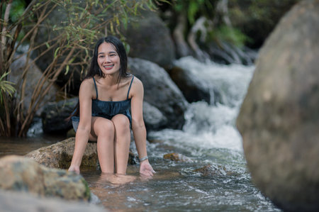 A young woman relaxes in a serene forest stream, enjoying natureの写真素材