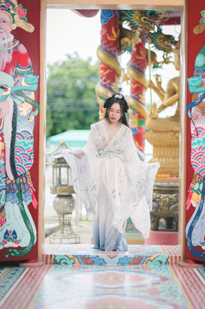 A young woman dressed in elegant Hanfu stands gracefully in a vibrant setting, showcasing the beauty of traditional Chinese culture and fashion.の写真素材