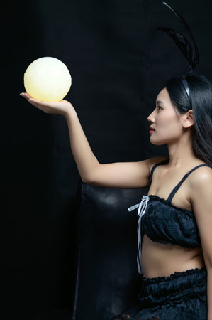 A captivating portrait of a woman in a ghostly bunny costume, elegantly holding a glowing sphere. This mysterious and stylish image exudes charm and creativity.の写真素材