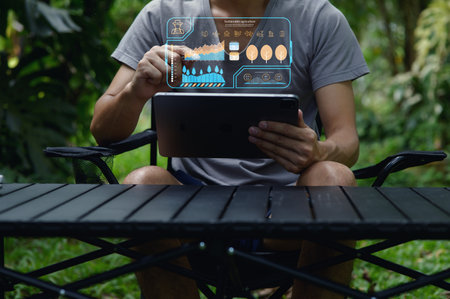 A person analyzes sustainable technology data using a tablet in a lush outdoor setting, showcasing innovative solutions for environmental management and resource efficiency.の写真素材