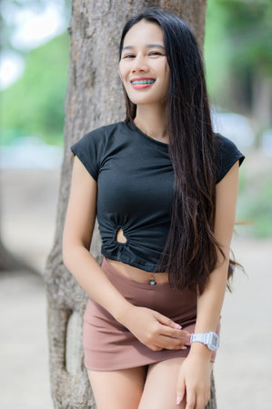 A cheerful woman in a black shirt and brown skirt smiles brightly outdoors, capturing the essence of natural beauty.の写真素材