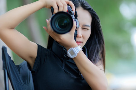 A woman wearing a black shirt and brown skirt captures stunning beach moments with her camera. Enjoy a summer day in a beautiful forest setting.の写真素材