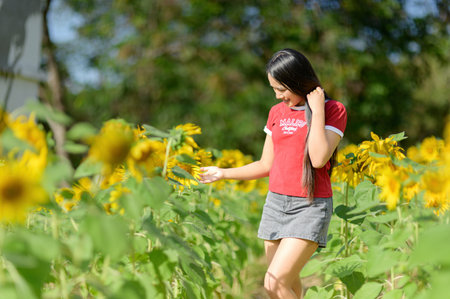 A young woman enjoys a sunny day among vibrant sunflowers, immersed in nature's beauty. The colorful landscape reflects joy and tranquility, perfect for outdoor moments.の写真素材