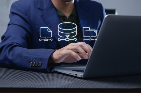 A business professional engages with a laptop, showcasing network data management. Emphasizing modern technology and digital communication in a professional workspace.の写真素材