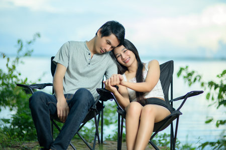A loving couple enjoys a serene moment by the lake, showcasing their affection and connection. Surrounded by nature, they create joyful memories together.の写真素材