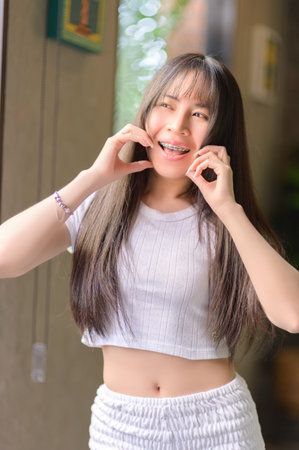 A young woman displays a joyful smile while showcasing her braces, standing in a bright indoor...