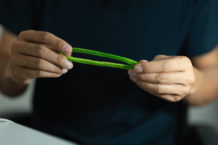A person holding a piece of green plant material with both hands, focusing on the natural texture and color in an indoor setting emphasizing eco-friendly and sustainable lifestyle concepts.