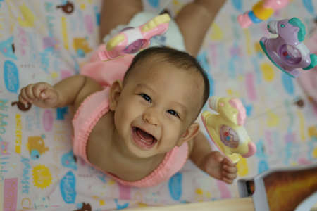 baby girl playing with a colorful mobile toyの写真素材