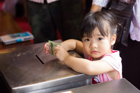 BANGKOK, THAILAND - October 3   Thai Buddhist baby girl donates banknote for Charity on October 3, 2013 のeditorial素材