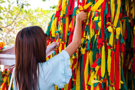 Colorful pieces of clothes on a tree by faith the people.の写真素材