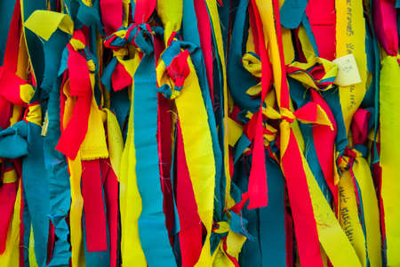 Colorful pieces of clothes on a tree by faith the people.の写真素材